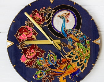May include: A blue and gold clock with a peacock design. The peacock is painted in shades of blue, green, and gold. The clock face is surrounded by flowers and leaves.