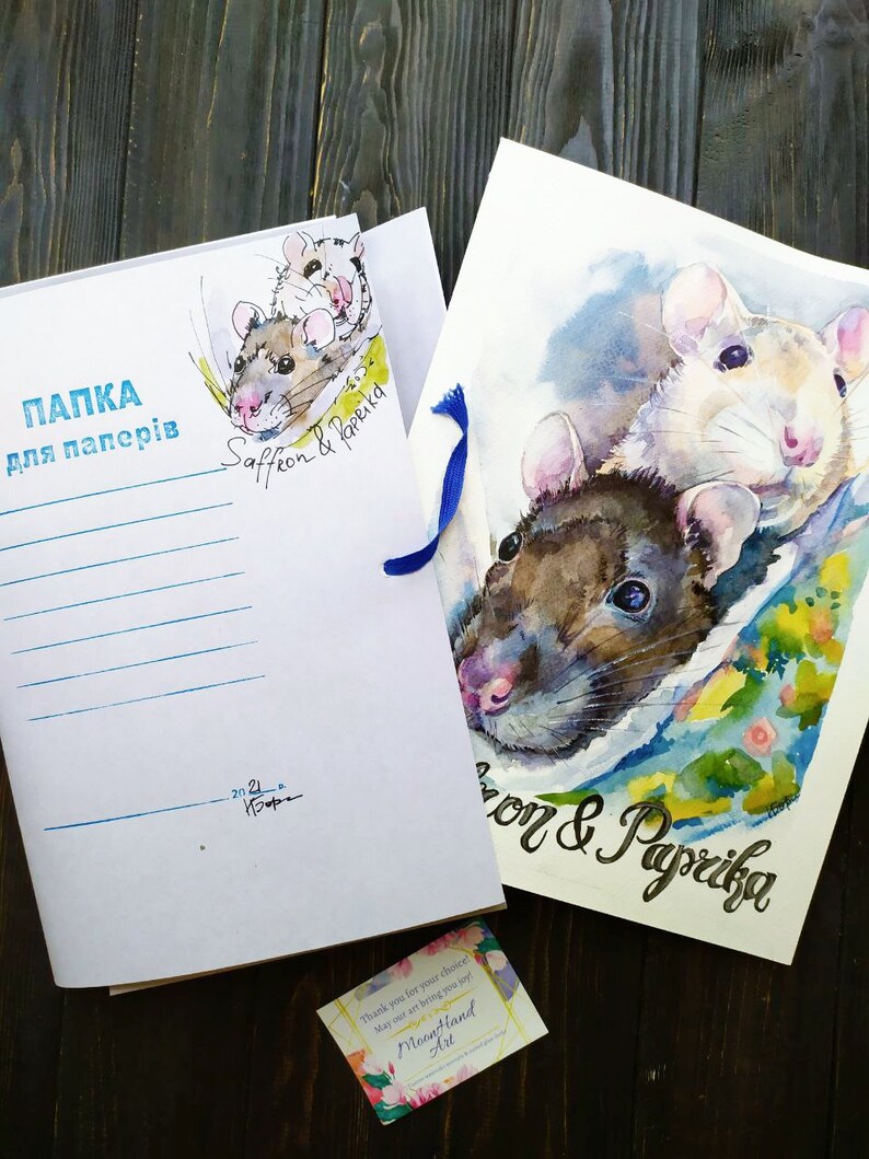 May include: A white folder with blue ribbon and the text "ПАПКА для паперів" in black. The folder has a watercolor illustration of two rats with the text "Saffron & Paprika" in black. A business card with the text "MoonHand Art" is in the bottom right corner.