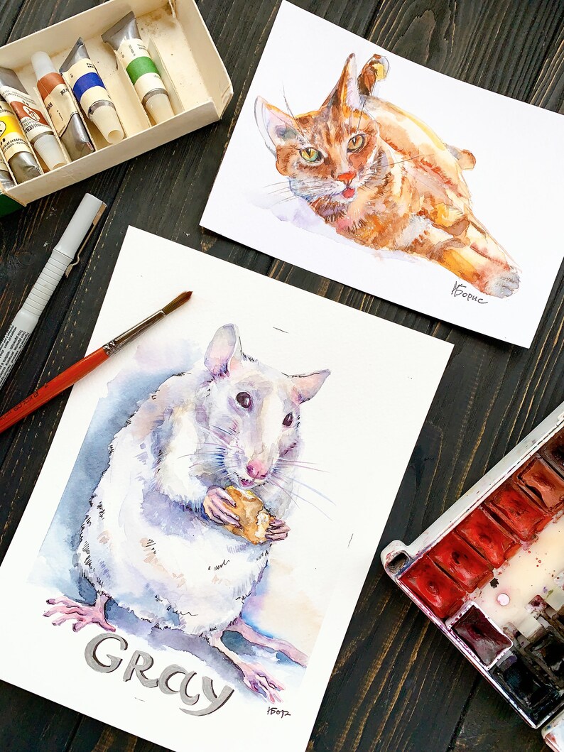 May include: Watercolor paintings of a ginger cat and a white rat, with the word "GRAY" below the rat. The cat is lying down, and the rat is holding a piece of food. Paint tubes, a paintbrush, and a watercolor palette are also visible.