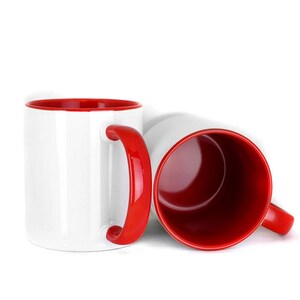 May include: Two white ceramic mugs with red interiors and red handles. The mugs are placed side by side on a white surface.