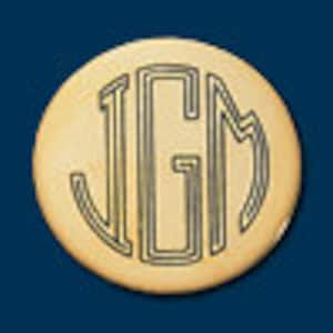 May include: A round, wooden disc with the letters "JGM" engraved in a monogram style.