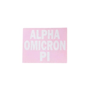 May include: A light pink rectangular patch with the white text "ALPHA OMICRON PI" in a bold, sans-serif font. The patch has a textured appearance.