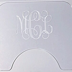 Op de afbeelding: Een transparante acryl onderzetter met een monogram. Het monogram is in een schrijfletter en luidt "MGL".