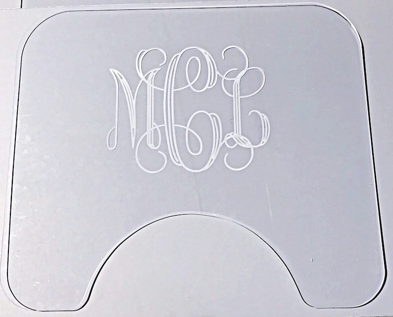 Op de afbeelding: Een transparante acryl onderzetter met een monogram. Het monogram is in een schrijfletter en luidt "MGL".