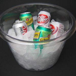 May include: A clear plastic ice bucket filled with ice and various soda cans, including Diet Coke, Dr Pepper, Schweppes, and Pepsi.