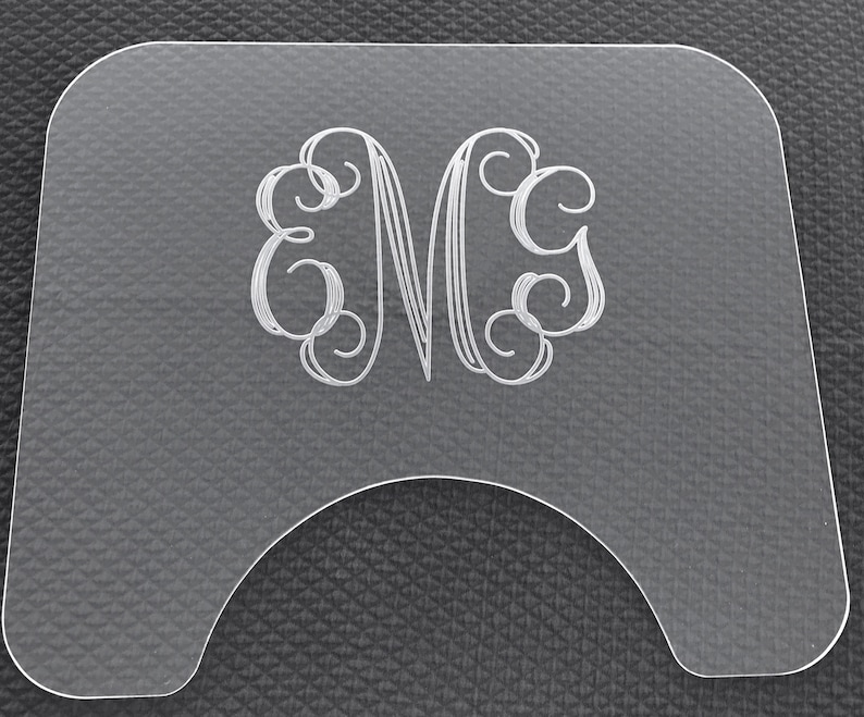 Op de afbeelding: Een helder acryl bord met een monogram van de letter "M" in een decoratief schrift.