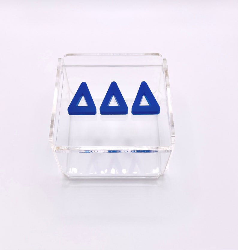 Pu&ograve; includere: Tre forme triangolari blu all'interno di una scatola in acrilico trasparente.