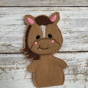 May include: Brown felt finger puppet of a horse with a white stripe down its face, pink ears, and a stitched smile.