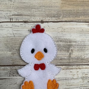 May include: White felt applique of a chick with red comb, orange beak, and feet, and a red bow tie.