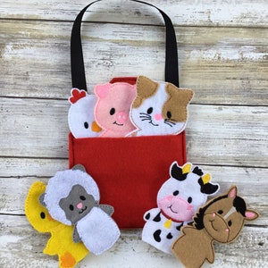 May include: A red felt bag with a black handle and five felt finger puppets. The puppets are a chick, pig, cat, sheep, cow, and horse. The puppets are all white with different colored accents.