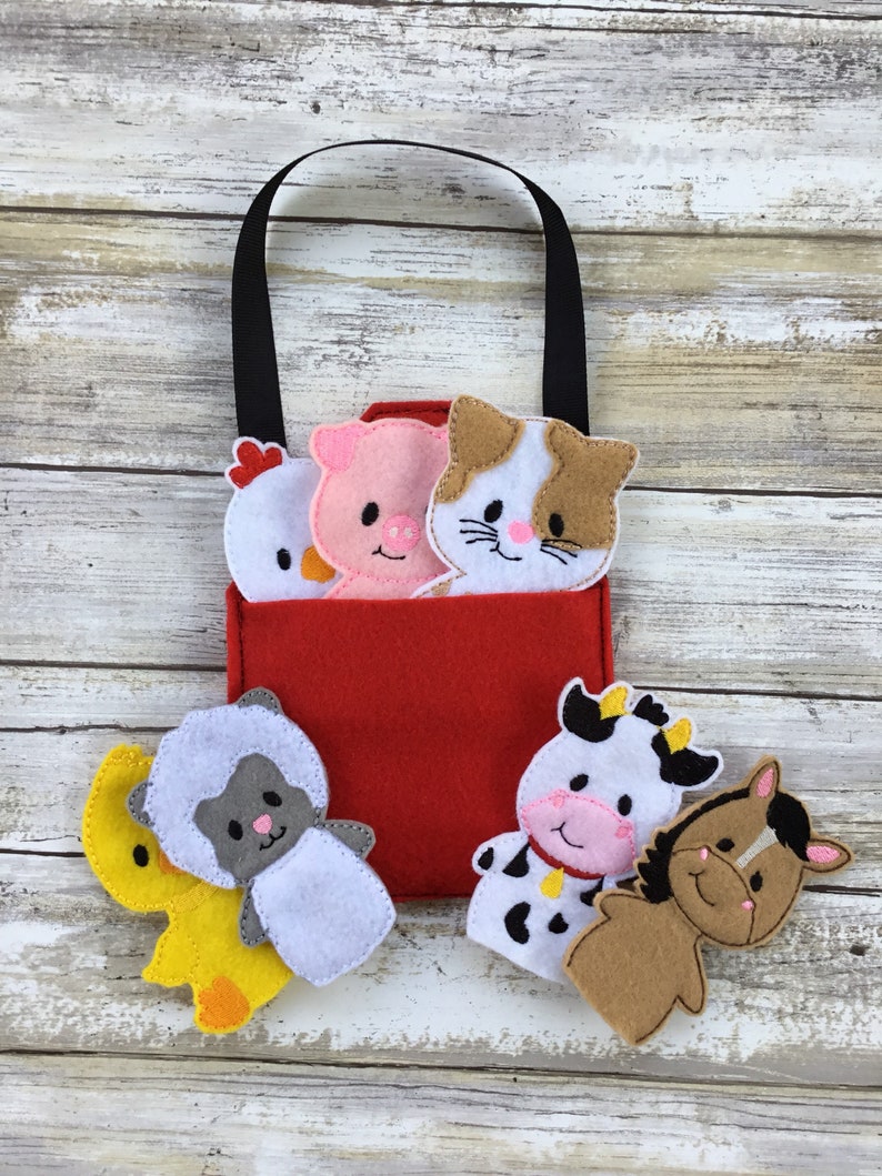 May include: A red felt bag with a black handle and five felt finger puppets. The puppets are a chick, pig, cat, sheep, cow, and horse. The puppets are all white with different colored accents.