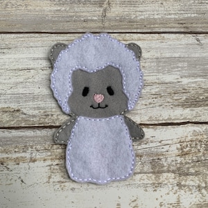 May include: A gray felt finger puppet shaped like a sheep with a white fluffy body and a pink nose.
