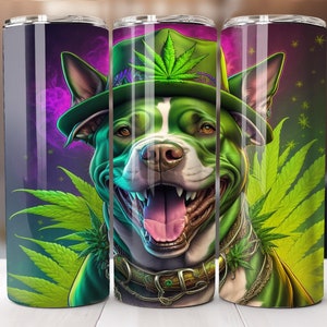 May include: A green and white pit bull dog wearing a green hat with a marijuana leaf on it. The dog is surrounded by green marijuana leaves. The background is a purple and black galaxy.