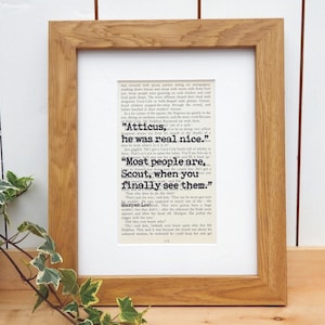 May include: A framed print of a page from the book "To Kill a Mockingbird" by Harper Lee. The text features a quote from the book: "Atticus, he was real nice. Most people are, Scout, when you finally see them."