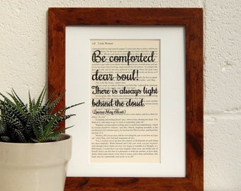 May include: A framed print of a book page with a quote from Louisa May Alcott's "Little Women." The quote reads, "Be comforted dear soul! There is always light behind the cloud." The print is on a white background and has a brown frame.