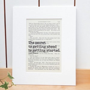 May include: A close-up of a page from a book titled "Huckleberry Finn". The text on the page reads "The secret to getting ahead is getting started."