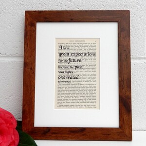May include: A framed print of a page from the book Great Expectations by Charles Dickens. The text reads "I have great expectations for the future, because the past was highly overrated."