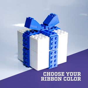 May include: A white Lego gift box with a blue ribbon bow. The text "CHOOSE YOUR RIBBON COLOR" is below the box.