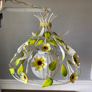 May include: White metal chandelier with yellow and green floral accents. The chandelier has a white globe-shaped light fixture.