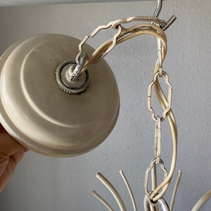 May include: White ceiling light fixture with a chain and a white ceiling plate. The light fixture has a starburst design with multiple arms.