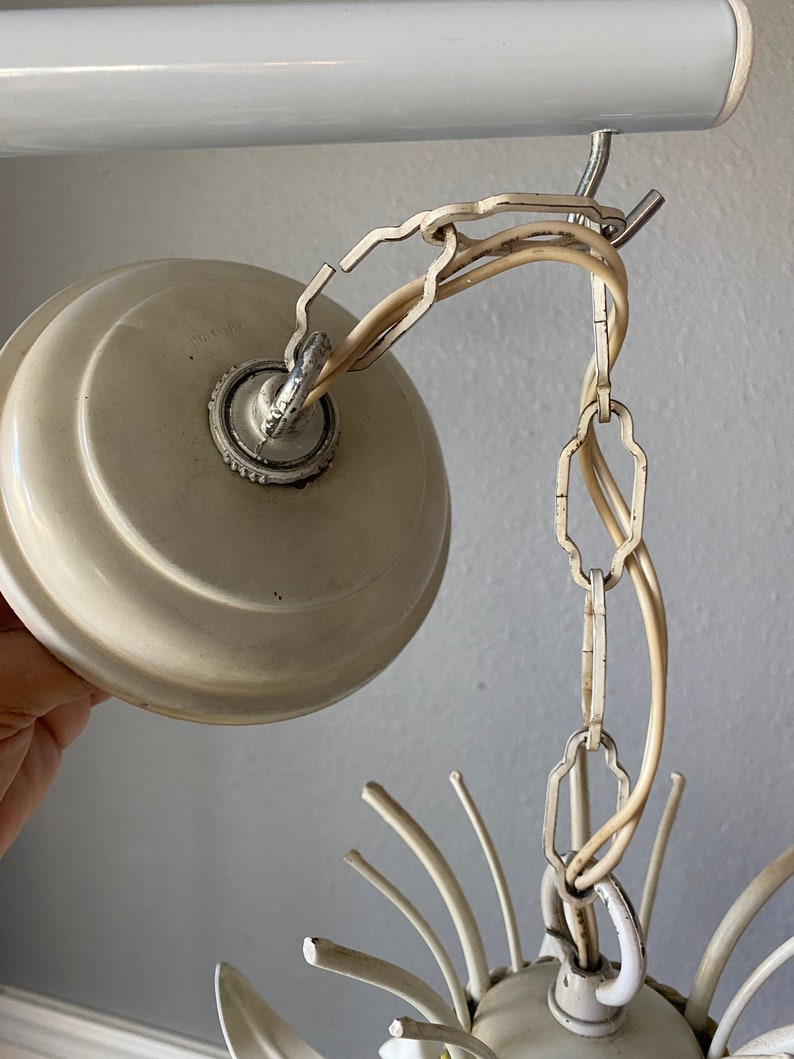May include: White ceiling light fixture with a chain and a white ceiling plate. The light fixture has a starburst design with multiple arms.