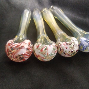 May include: Four glass smoking pipes with colorful swirl designs. The pipes are clear glass with a white, red, green, and blue swirl design.