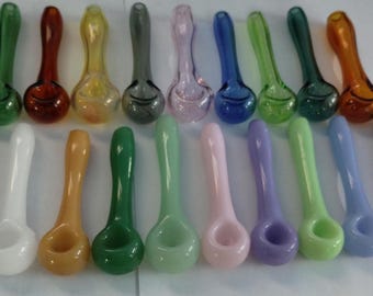 Può includere: Una collezione di 20 pipe da fumo in vetro di vari colori, tra cui blu, verde, bianco e arancione. Le pipe sono disposte in due file, con un accendino sullo sfondo.