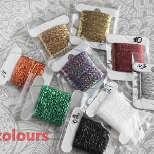 Può includere: Nove bobine di filo da ricamo metallizzato in vari colori, tra cui oro, argento, rosso, verde, nero, bianco e iridescente. Le bobine sono numerate.