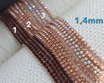 May include: Close-up of three rows of rhinestone trim in rose gold, black, and iridescent colors. The trim is 1.4mm wide.