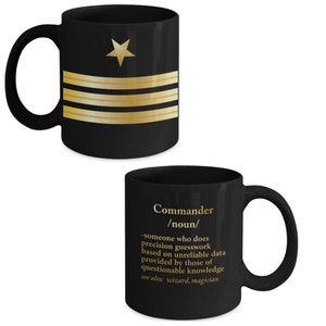 May include: Black ceramic coffee mug with a gold star and stripes design. The other side of the mug has the word "Commander" in gold lettering with a definition: "someone who does precision guesswork based on unreliable data provided by those of questionable knowledge. see also: wizard, magician"