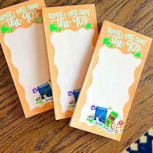 Puede incluir: Tres blocs de notas de color naranja con el texto "Things I Miss About the 90's" en letras verdes y blancas. Cada bloc de notas tiene una ilustración diferente con temática de los 90, incluyendo una caja de Capri Sun, una lata de Surge y una caja de Pop-Tarts.