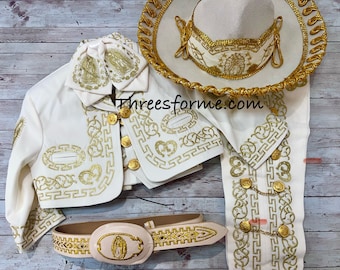 May include: A white charro suit with gold embroidery. The suit includes a jacket, pants, a belt with a buckle, and a sombrero. The embroidery features a traditional Mexican design.