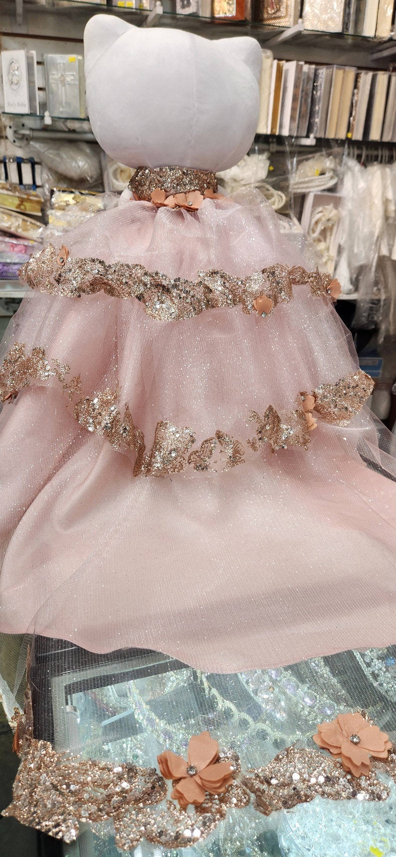 May include: A pink tulle dress with gold glitter and floral embellishments. The dress is layered and has a white plush cat head on top.