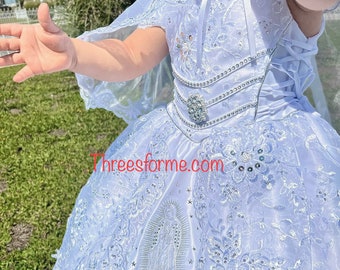 May include: White lace dress with a cape, featuring a silver embroidered image of the Virgin Mary. The dress has a lace bodice with a silver rhinestone belt and a lace skirt with silver sequins.