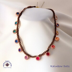 May include: A handmade necklace with a brown beaded chain and colorful, round, beaded accents. The accents are in shades of red, orange, yellow, green, blue, and purple. The text "Rainbow Dots" is visible.