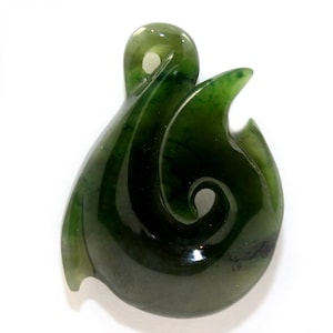 May include: A polished, dark green jade pendant with a swirling, curved design. The pendant has a smooth, glossy finish and a small loop at the top for a necklace. The overall shape is reminiscent of a stylized hook or wave.