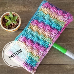 May include: A colorful crochet mop head with a rainbow pattern. The mop head is made with a variety of colors, including pink, blue, green, and yellow. The mop head is attached to a green mop handle.
