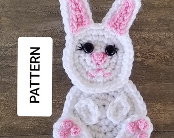 May include: White crocheted bunny applique with pink ears, nose, and feet. The bunny has black eyes and a smiling mouth.