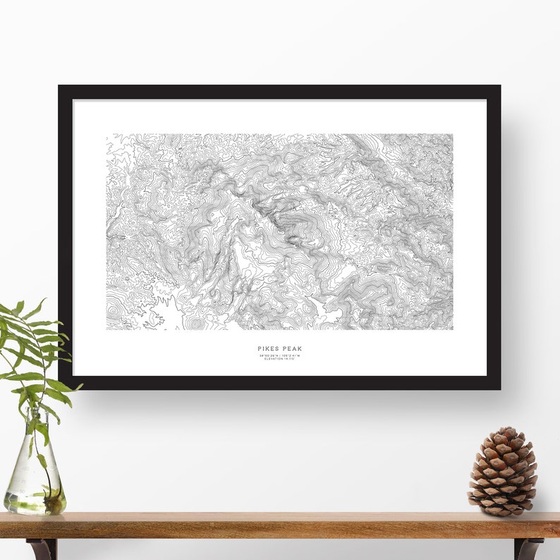 K&ouml;nnte beinhalten: Ein Schwarzwei&szlig;-Druck einer topografischen Karte des Pikes Peak in Colorado. Der Druck zeigt die H&ouml;henlinien des Berges. Der Text "Pikes Peak" und "Elevation 14,115 ft" ist unten auf der Karte gedruckt.