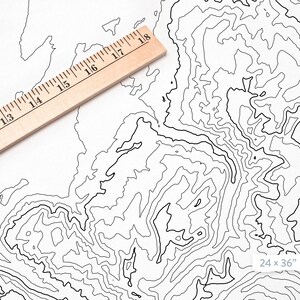 May include: A black and white topographic map print with contour lines. The print is 24 inches by 36 inches. A wooden ruler is placed on the top of the print.
