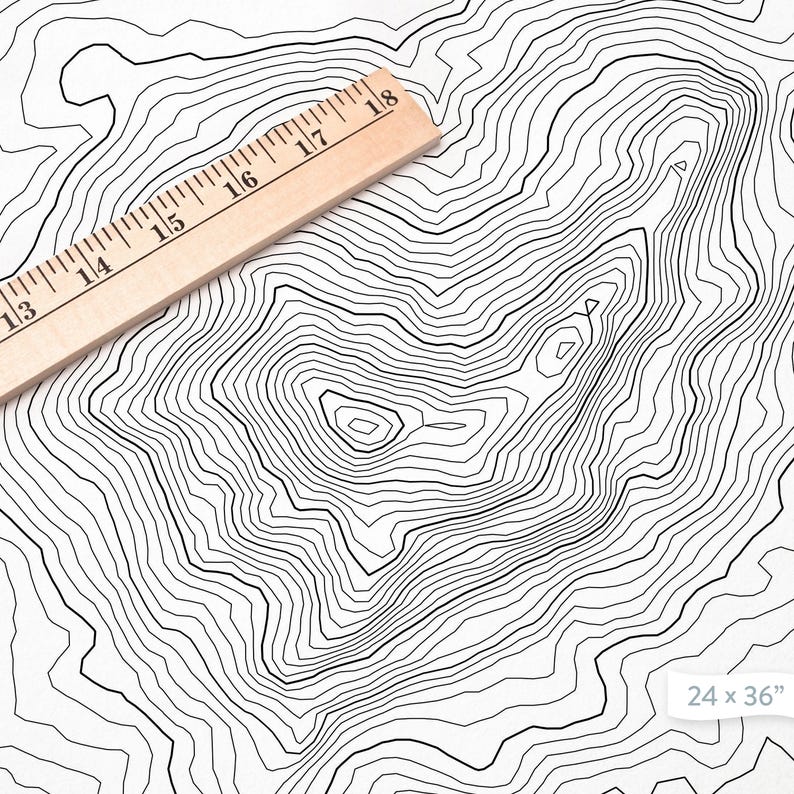 May include: A black and white topographic map print with concentric circles, resembling a mountain range. A wooden ruler is placed diagonally across the print. The print measures 24 x 36 inches.
