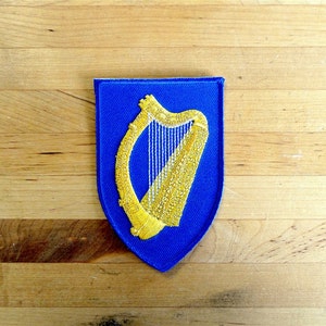 Puede incluir: Un parche de fieltro azul con un arpa bordada en oro, símbolo de Irlanda.