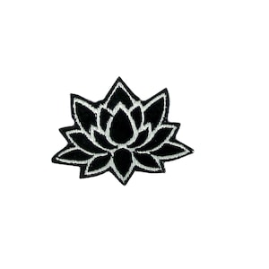 Pode incluir: Patch de flor de lótus bordada em preto. A flor tem um contorno branco e é um símbolo popular de paz e pureza.