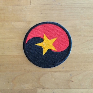 May include: A black and red circle with a yellow star in the center. The circle is a yin-yang symbol with the black half on the left and the red half on the right.