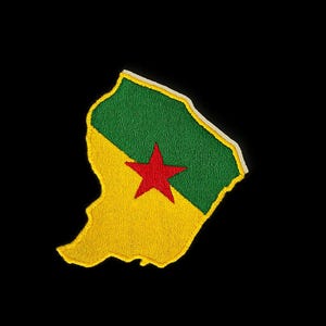 Può includere: Toppa ricamata a forma di Guyana francese, con un design giallo e verde e una stella rossa. La toppa ha un bordo bianco ed è posta su uno sfondo nero.