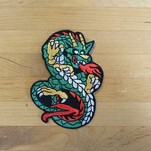 Può includere: Toppa da stirare ricamata di colore verde, rosso e giallo di un drago con gli artigli all'esterno.