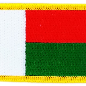 Puede incluir: Un parche de tela con la bandera de Madagascar. La bandera es una franja horizontal tricolor de blanco, rojo y verde con un borde amarillo.