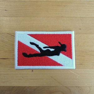 May include: A white and red scuba diving flag patch with a black silhouette of a diver.