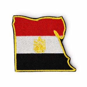 Puede incluir: Parche bordado con la forma de Egipto, con la bandera del país. El diseño de la bandera incluye franjas horizontales rojas, blancas y negras, con un emblema dorado en el centro. El parche tiene un borde amarillo.