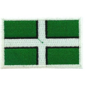 May include: Embroidered patch featuring the flag of Devon, England. The design includes a white cross on a green background, with a black border. The patch has a white stitched border.